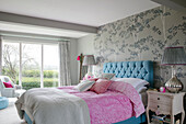 Hellblaues Bett mit rosa Bettdecke und Blick auf die Landschaft von Hampshire England UK