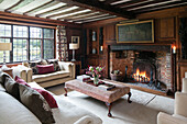 Ottoman and cream sofas in living room with lit fire in Kent farmhouse UK