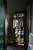 Wardrobe of clothes reflected in full length mirror with woodwork painted in Studio Green Welsh barn conversion UK