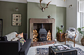 Wall in 'Lichen' with sheepskin antlers and fire surround made from old stone gate posts in Cumbrian terrace UK