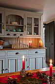 Willow basket and lit candles on dresser painted Paris Grey in Norfolk farmhouse kitchen UK
