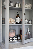 Toiletries in glass fronted bathroom cabinet in Surrey cottage UK