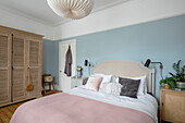 Pastellrosa und blaues Schlafzimmer mit Lamellenschrank aus Eiche in einem viktorianischen Familienhaus Manchester UK