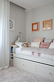 Day bed with grey wash and pastel pink cushions in teen room London UK