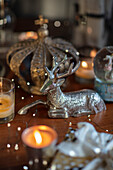 Silbernes Rentier und brennende Kerzen auf einem Mahagoni-Tisch in einem Landhaus in Berkshire UK