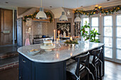 Kücheninsel mit weißen Pendelleuchten und Weihnachtsgirlanden in einem Landhaus in Berkshire UK