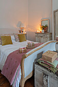 Bettgestell aus verwitterter Eiche mit Überwurf in Dusky Pink und gelben Samtkissen in einem Schlafzimmer in Hampshire UK