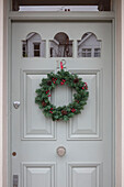 Christmas wreath with light grey paintwork on door of number 12 London UK