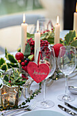 Herzförmiges Namensschild und Weingläser mit Stechpalme auf einem Esstisch in einem Londoner Haus, UK
