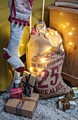 Weihnachtsstrumpf mit Sack und Geschenken am Bett in einem Haus in Surrey, England