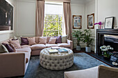Pastel pink sofa with buttoned ottoman in London townhouse UK