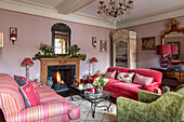 Pink sofas and green armchair with lit fire in Grade II listed Georgian country house West Sussex UK