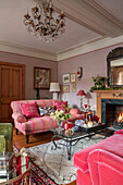Striped pink sofa and coffee table with antique chandelier in Grade II listed Georgian country house West Sussex UK