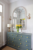 Yellow tulips on hallway chest with arched mirror in Victorian villa Tunbridge Wells Kent UK
