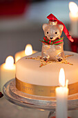 Tree ornament on Christmas cake with lit candles Hampshire UK