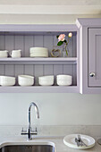 White crockery in wall mounted shelving above kitchen sink Surrey UK