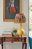 Lamp on walnut desk with books and artwork London UK