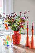 Cut flowers and candles with bright red vase London UK