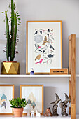 Framed artwork and cactus with dominos on shelf in Sussex home UK