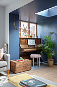 Klavier und Holzkiste unter Oberlicht in blauem Zimmer Sussex UK