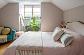 Rosa Bettdecke auf Doppelbett mit Farn am Fenster Sussex UK