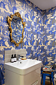 Oriental wallpaper with gilt framed mirror above basin Sussex UK