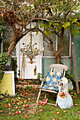 Folding chair at back door under apple tree with chandelier Isle of Wight, UK