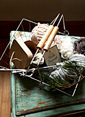 Variety of wools with knitting needles in wire basket Isle of Wight, UK
