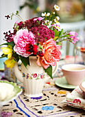 Cut flowers on crochet tablecloth with teacup in Isle of Wight home UK