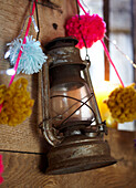 Rusty hurricane lantern and pompoms in wood cabin UK