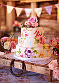 Floral iced cake and horseshoe with bunting in wooden barn late summer UK