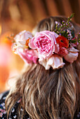Woman wears garland of pink roses in her hair late summer