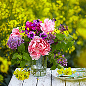 Schnittblumen auf dem Tisch in einem Feld mit blühendem Raps (Brassica napus)