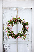 Pretty spring floral wreath made with pink blossom against door with lace curtain