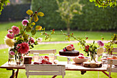 Spätsommerpicknick im Garten mit Kuchen, Obst und Blumen