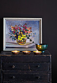 Dunkler Vintage-Schrank und -Wand mit floralem Vintage-Kunstwerk und Teelichtern