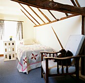 Schlafzimmer im Dachgeschoss mit Eichenbalken und antiker amerikanischer Steppdecke