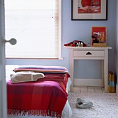 Pastellblaues Schlafzimmer mit bunten Decken, Wärmflasche und Hausschuhen aus Filz