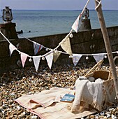 Picnic blanket and basket on a pebbled beach with bunting 