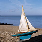 Vintage toy sailing boat on a shingle beach