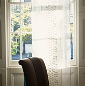 Voile Vorhangstreifen an einem georgischen Fenster mit Stuhllehne