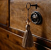Gold coloured tassel attached to a vintage key in a wooden chest of draws