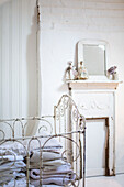 Vintage Wirework cot in white room with dolls above a painted fireplace