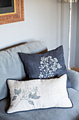 Grey and white floral embroidered cushions on a sofa