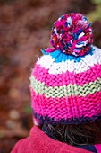 Close up of pink stripey woolen hat with pom pom, Autumn, Haslemere, Surrey, England