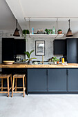 Modern kitchen unit in black with wooden accents and various indoor plants