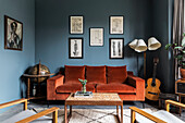 Wohnzimmer mit blauen Wänden, Vintage-Dekoration und orangefarbenem Samt-Sofa