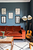 Living room with orange velvet sofa, guitar and retro floor lamp