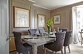Dining table with upholstered chairs in the living room with decorative paneled walls