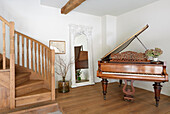 Wooden staircase and grand piano in a room with large mirror